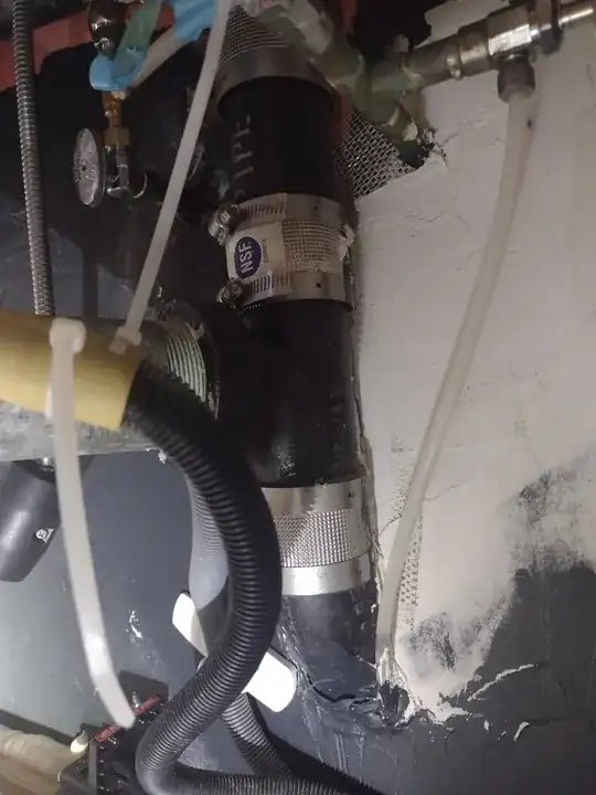 further back under the sink, showing the bottom of the vertical pipe elbowing into the wall