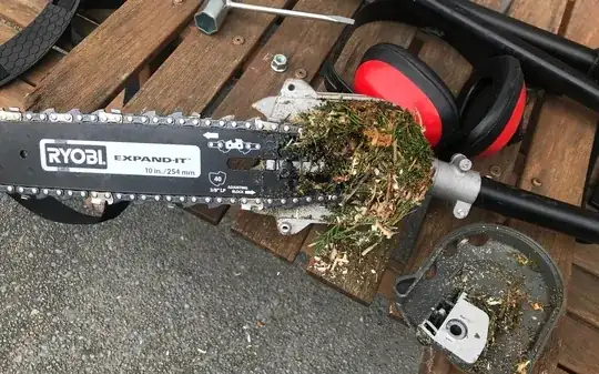 close up of chainsaw blade and chain, with plant debris wedging up the chain