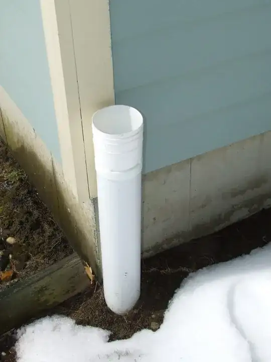 Another polyethylene sewer pipe emerging from ground exterior, adjacent to foundation