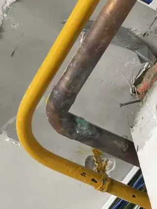 Yellow painted pipe next to oxidized copper pipe