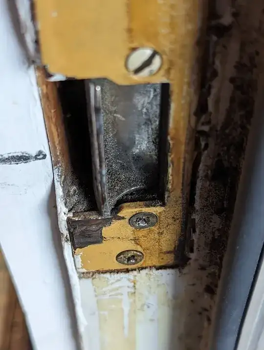 photo of strike plate in door frame. It has a curved, vertical piece of metal that has a few mm of give to it