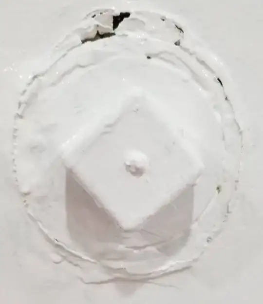 thickly painted square protrusion on round surface with cracked paint around perimeter