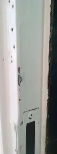 A view from the side of the door frame showing again that there is no place in the door frame for a bolt to go into, even if it could get through the side of the door (which it couldn't, at least now). At the bottom of the frame you can see where the bottom lock goes into the frame.