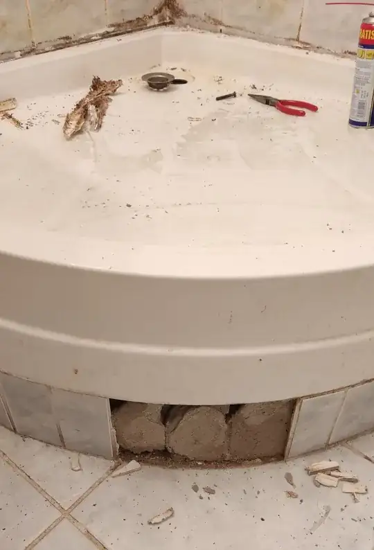 side view of shower tray showing 3 missing ceramic tiles and the cement(thin-set mortar?) underneath them