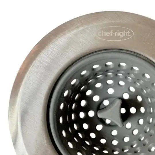 closeup of a metal drain strainer with small holes and a plastic handle in the centre