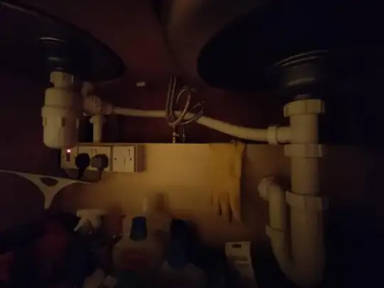 Image of plumbing under the kitchen sinks, showing a bottle trap and a p trap.