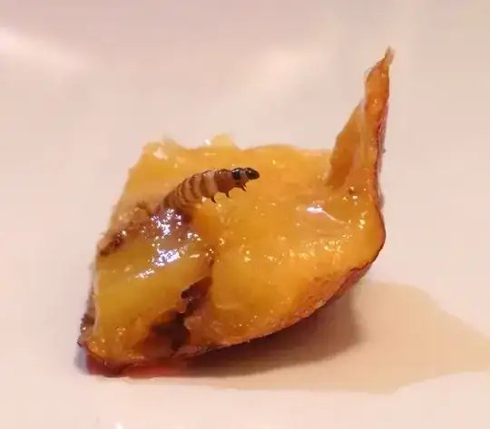 Closeup of larva and the flesh of the fruit cut just beneath the hole.