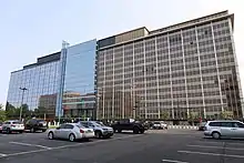 A photo of a building whose left side is blue glass, and right side is brown