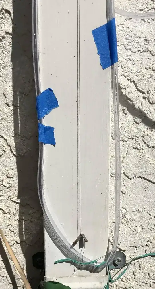 Airline hose water manometer with black thread plumbline dropped in the middle secured against rain gutter downspout