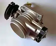 Throttle body showing throttle position sensor. The throttle cable attaches to the curved, black portion on the left. The copper-coloured coil visible next to this returns the throttle to its idle (closed) position when the pedal is released.