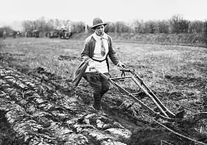 Members of the Women's Land Army operates a single-furrow plough on a British farm in 1914.