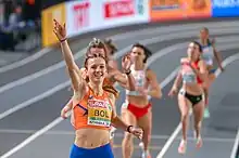Photo of Femke Bol holding one hand in the air while finishing ahead of the other competitors