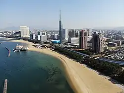 Aerial view of the seaside Momochi&nbsp;[ja] with the Fukuoka Tower and Momochi Seaside Park in the center and with the Fukuoka PayPay Dome to the left side