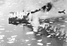 A ship sailing on a body of water amidst lumps of ice and explosions in the water