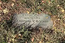 Flat memorial marker in a cemetery. The text reads "In loving memory, wife - mother, Josephine V. Bogash, March 3, 1897-December 18, 1960).