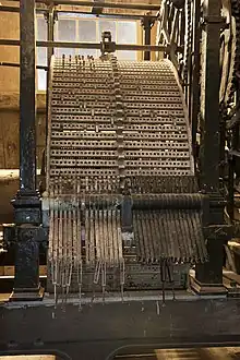 Large metal cylinder with pegs connected to gears.