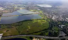 Image 9Seven reservoirs.  View of four in Spelthorne with small lakes of lower elevation, from aggregate extraction, in the south of the borough to the right.  Beyond three reservoirs in Elmbridge.  The flattest areas of the far north of the county. Staines road and rail bridges span the Thames into Runnymede in the right of the photograph. (from Portal:Surrey/Selected pictures)