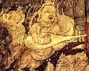 India, in Ajanta Caves, Cave 1, c. 450-490 AD. Kinnara with "kacchapī veena" (Sanskrit for "tortise veena") or panchangi veena (5-stringed veena). Part of the painting Bodhisattva Padmapani.