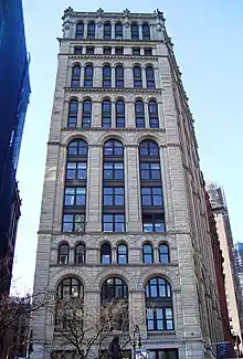 A multi-story white Romanesque building, seen looking up from street level