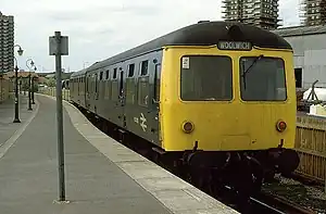 Train with yellow front has destination blind that reads 'Woolwich'
