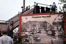An observation deck in West Berlin with a view of Potsdamer Platz on the other side of the Berlin Wall, 1977. At the bottom of the steps a placard shows what the square looked like in 1929.