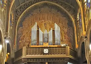 The organ in the tribune of the nave, in front of a painting of a choir of angels