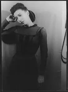 A young woman, standing, in a dark dress