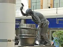 Statue of a cooper hammering a shaping truss over the staves of a barrel