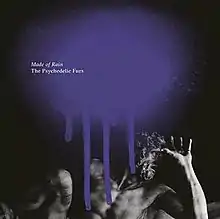 A black-and-white photo of a sculpture of a man with a long beard covering his face with a large splatter of purple paint on the top and the album and band name in white type
