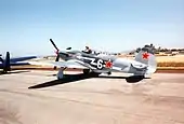  Propeller fighter on tarmac with pilot standing up in open cockpit. Red star