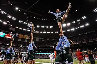 Several women held in the air kicking with men below them